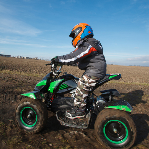 Child riding a electric ATV quad, wearing motorsport suit and helmet