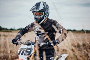Adult man riding a dirt bike with a black wulfsport safety helmet on
